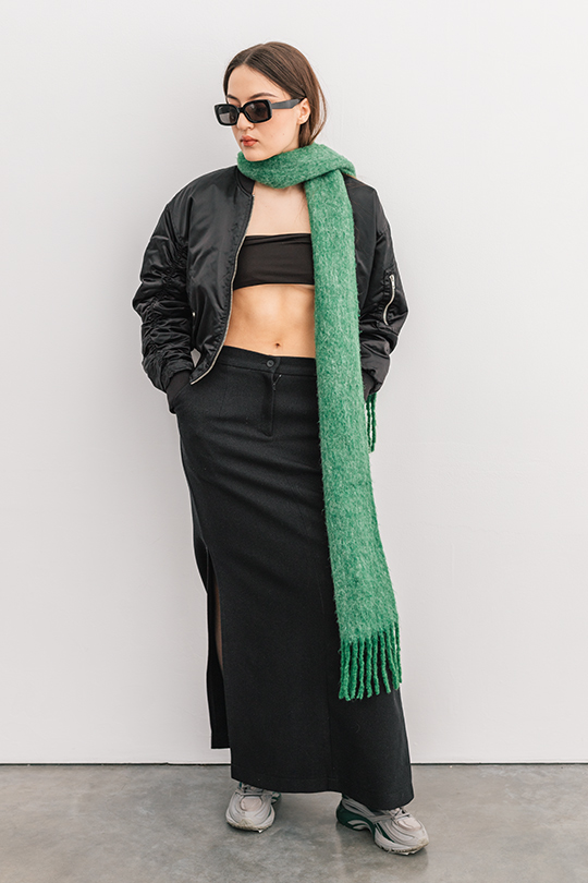 Фото девушки в черном наряде с длинным зеленым шарфом. 
